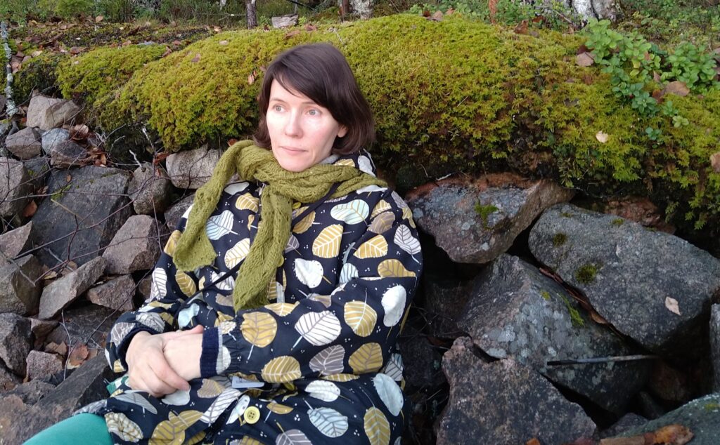 Kaisa Leinonen istuu rannalla